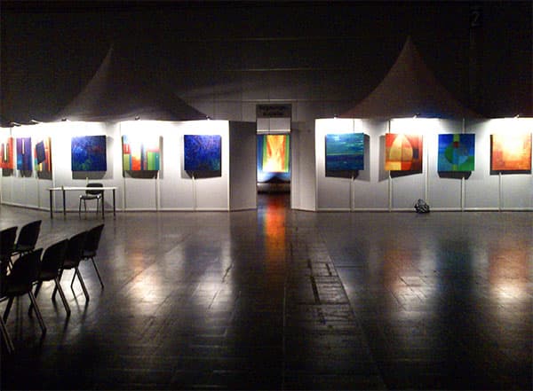 Weiter Blick in die Ausstellungshalle der Messe Leipzig mit Gemälden und Sitzreihen